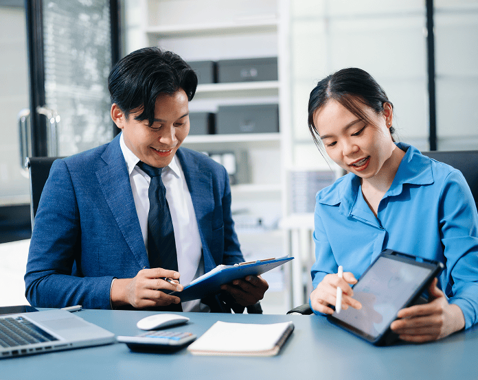 Colleagues discuss work with tablet and documents.