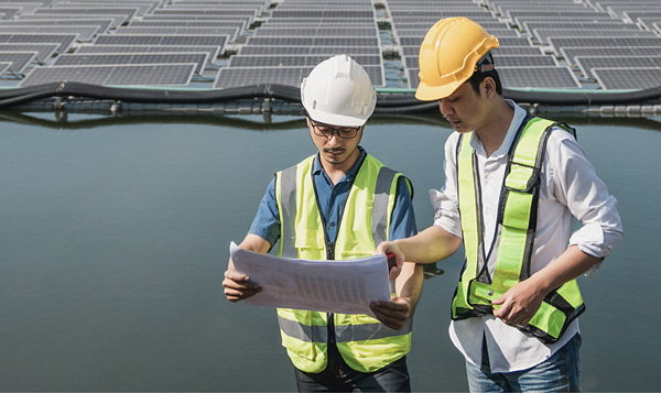 Engineers inspecting solar panels on water.