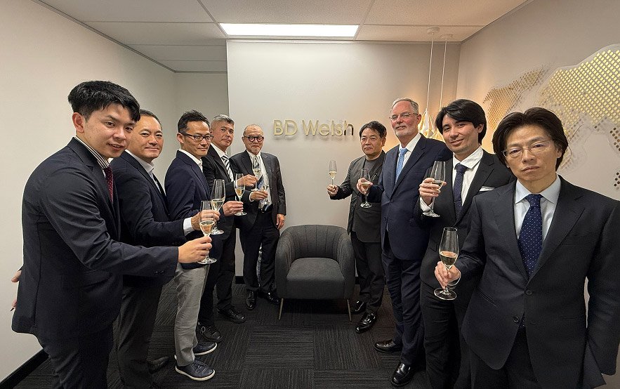 Group celebrates at BD Welsh office with champagne.