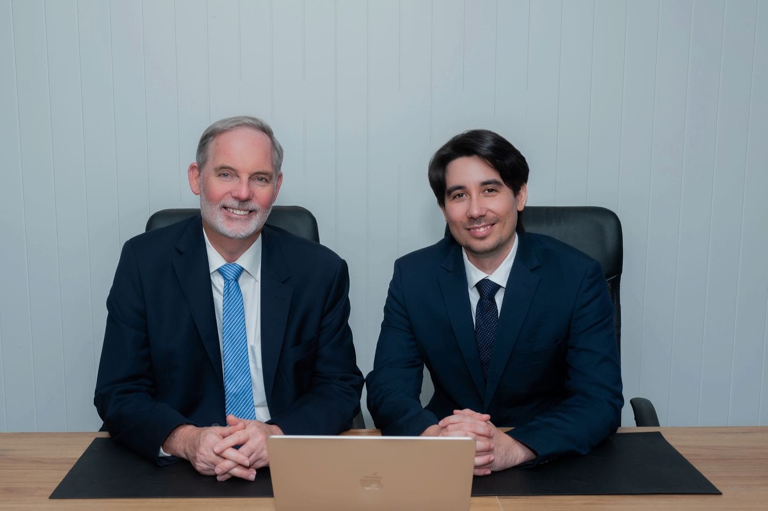 Two businessmen seated at desk with laptop