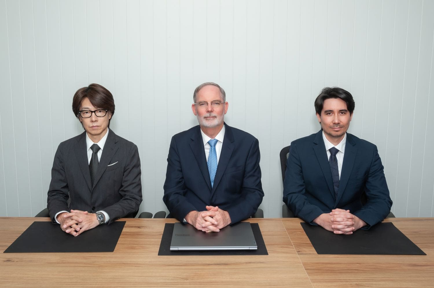 Three businessmen seated at conference table with laptop